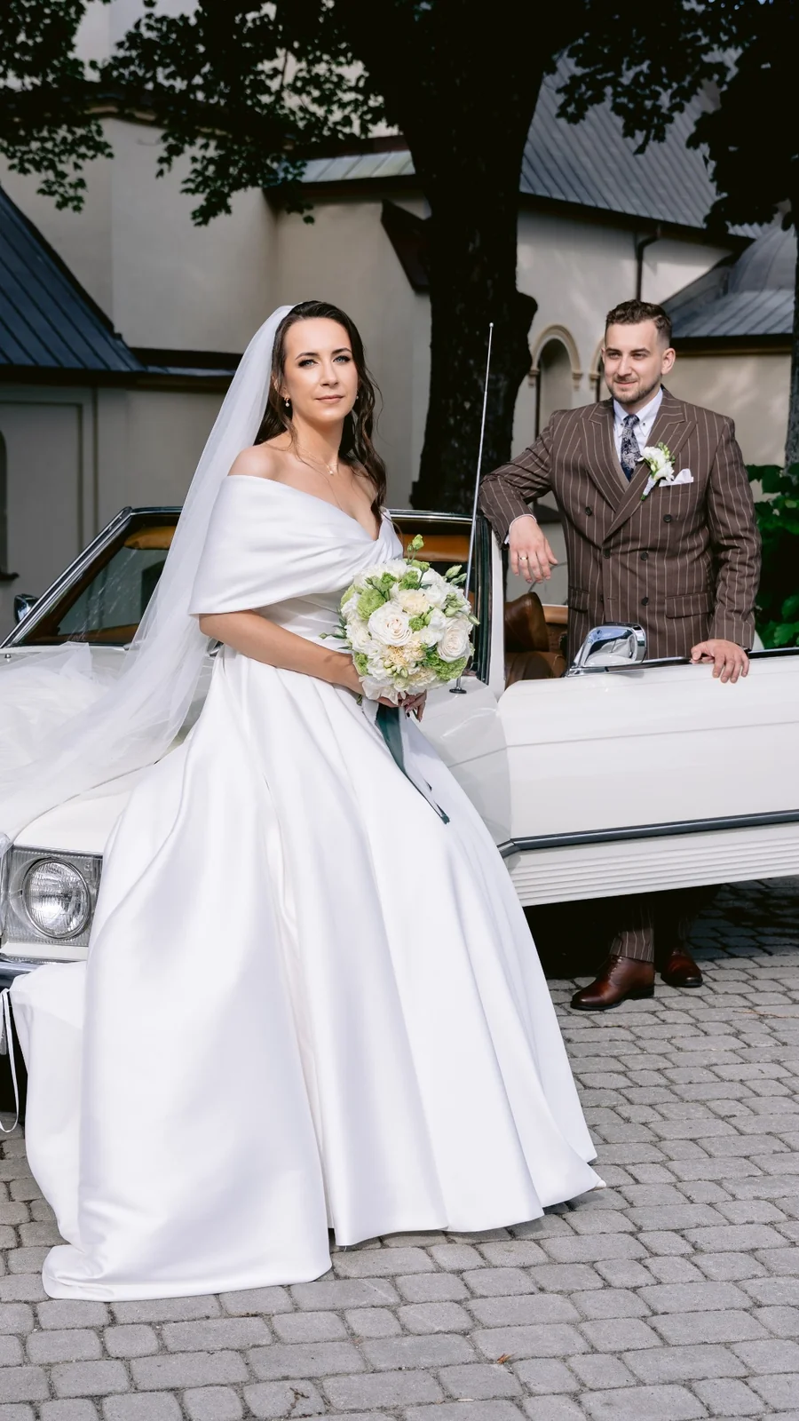 Para młoda przy zabytkowym samochodzie w dniu ślubu